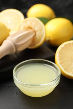Taze limon suyu, meyveler ve sıkma siyah ahşap masa, yakın plan.