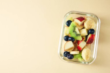 Bej arka planda cam kabın içinde lezzetli meyve salatası, üst manzara. Metin için boşluk