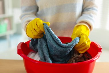 Kadın çamaşırları plastik bir leğenle yıkıyor, kapalı bir masada, yakın plan.