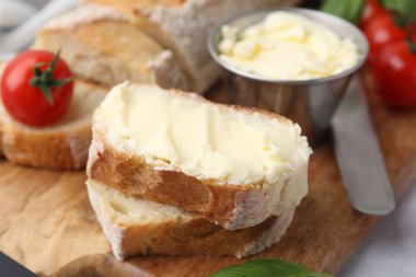 Tereyağlı baget, fesleğen, domates ve bıçaklı ekmek, yakın plan.