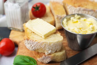 Tereyağlı baget, fesleğen, domates ve bıçaklı ekmek, yakın plan.