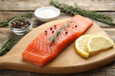 Bir parça somon fileto, baharat ve limon ahşap masada, yakın plan.