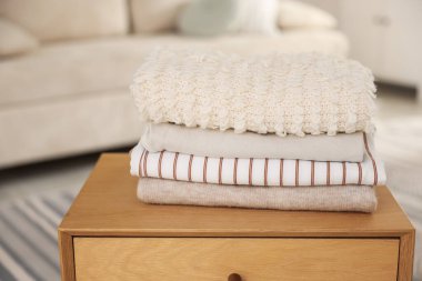 İçerideki ahşap komodinin üzerinde temiz giysiler yığını, yakın plan. Metin için boşluk