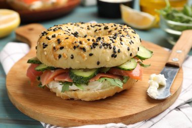 Somon, krem peynir, salatalık, roka ve limonlu leziz simit açık mavi ahşap masa, yakın plan.