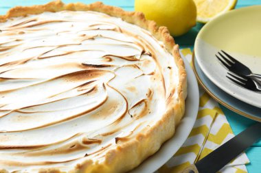 Turkuaz ahşap masada servis edilen lezzetli limonlu turta, yakın plan.
