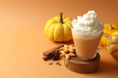 Krem şantili, baharatlı, kurabiyeli ve turuncu arka planda taze sebzeli balkabaklı latte. Metin için boşluk