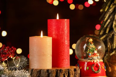 Masada yanan mumlar ve Noel dekoru. Arka planda bulanık ışıklar, yakın plan. Bokeh etkisi