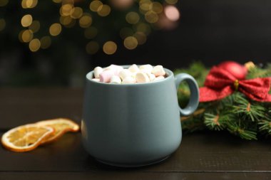 Tahta masada lokum kaplı lezzetli sıcak kakao bulanık Noel ışıklarına karşı, yakın plan.