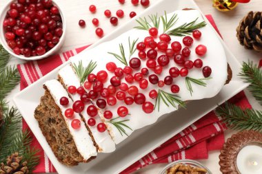 Beyaz ahşap masada kremalı, yaban mersinli, biberiyeli ve şenlikli bir Noel pastası.
