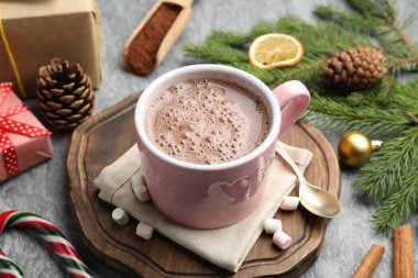 Lezzetli kakao, marşmelov, tarçın, şeker kamışı ve Noel süsü gri masada, yakın plan.