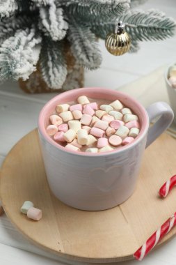 Marşmelovlu lezzetli kakao ve beyaz ahşap masada Noel dekoru, yakın plan.