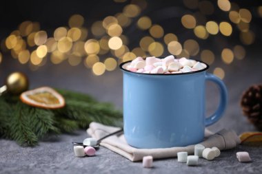 Gri masasında lokum bulunan lezzetli kakao bulanık Noel ışıklarına karşı, yakın plan.