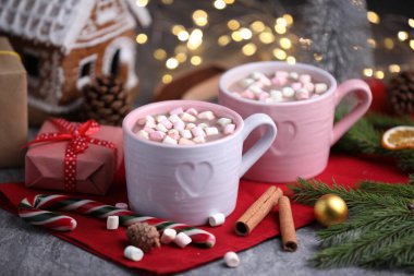 Gri masada lokum, tarçın ve Noel dekoru olan lezzetli kakao bulanık ışıklara karşı, yakın plan.