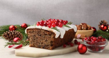Kremalı, kızılcıklı, fındıklı ve açık gri masada süslü bir Noel pastası. Yakın plan.