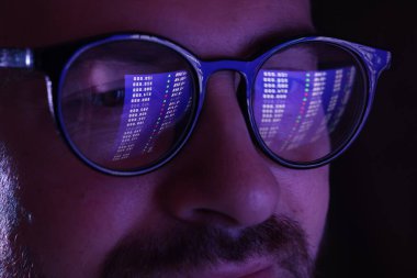 Siyah arka planda yansıması olan gözlüklü bir adam, yakın plan.