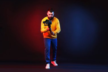 Kamerada çekim yapan kameraman, koyu arkaplandaki renk ışıklarına karşı titreşim dengeleyici kullanıyor.