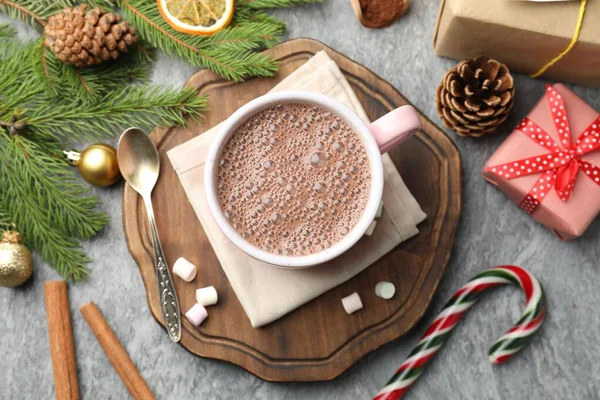 Lezzetli kakao, marşmelov, tarçın, şeker kamışı ve Noel süsü gri masada, düz uzanmış