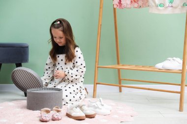 Küçük kız dükkanda farklı ayakkabılar arasında seçim yapıyor. Metin için boşluk