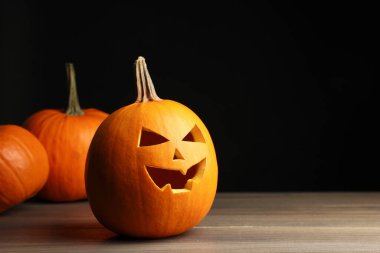 Cadılar Bayramı kutlaması. Tüm ve oyulmuş kabaklar ahşap masa üzerinde siyah arkaplan karşı, metin için yer