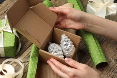 Kutlama ambalajı. Külahta mücevher kutusu olan bir kadın, ahşap masada kağıt ve kurdele, yakın plan. Mutlu Noeller ve mutlu yıllar.