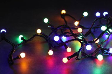 Parlak Noel ışıkları masada, karanlıkta, yakın plan. Yeni yıl tebrik kartı.