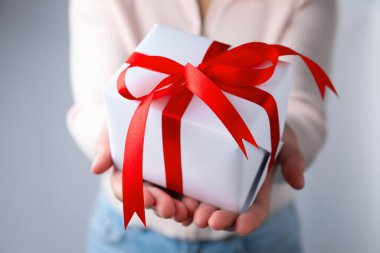 Woman with gift box on grey background, closeup