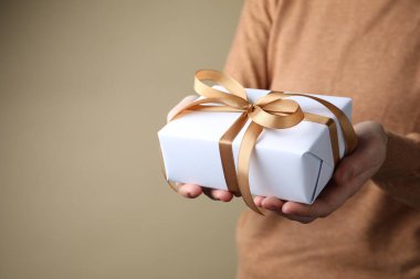 Bej arka planda hediye kutusu olan bir kadın, yakın plan. Metin için boşluk