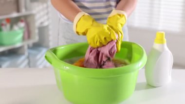 Beyaz masada plastik bir leğende çamaşırları yıkayan kadın, yakın plan. Kamera ileri gidiyor