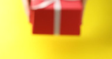 Sarı arka plana hediye kutusu koyan kadın, yakın plan.