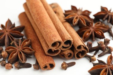 Sıcak şarap baharatları. Tarçın çubukları, anason yıldızları ve karanfiller beyaz ahşap masada, yakın plan