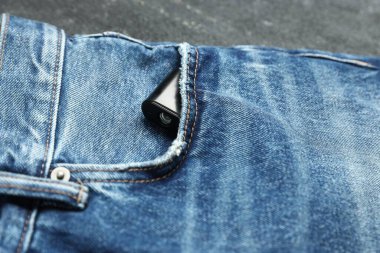 Siyah arka planda kot pantolon cebinde gizli casus kamerası, yakın plan.