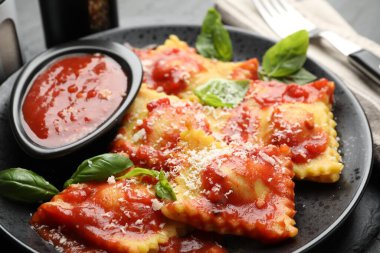 Gri masada servis edilen domates soslu, peynirli ve fesleğenli lezzetli ravioli.