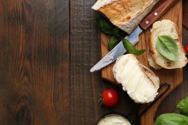 Tahta masada tereyağlı, fesleğenli, domatesli ve bıçaklı baget dilimleri. Metin için boşluk