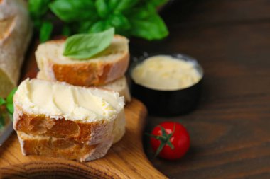 Tahta masada tereyağlı, fesleğenli ve domatesli baget dilimleri, yakın plan. Metin için boşluk