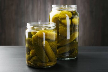 Kavanozda salatalık turşusu, siyah ahşap masa, yakın plan.