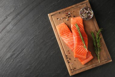 Somon fileto parçaları ve baharatlar siyah desenli masa, üst manzara. Metin için boşluk