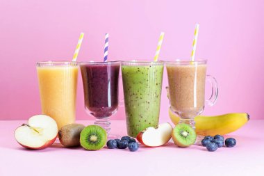 Farklı lezzetli içecekler, pembe arka planda bardaklar ve malzemeler.