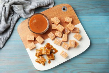 Açık mavi ahşap masada tuz ve karamel soslu lezzetli şekerler.