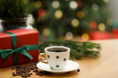 Kahve fincanında romatik kahve, fasulye ve hediye kutusu ahşap masada bulanık ışıklara karşı, yakın plan. Metin için boşluk