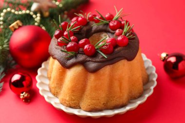 Kırmızı arka planda yaban mersinli lezzetli pasta ve Noel dekoru, yakın plan.