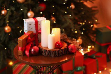 Kapalı alandaki Noel ağacının yakınındaki masada mum yakmak ve şenlikli bir dekor. Metin için boşluk