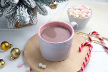 Lezzetli kakao, marşmelov, baston şekerler ve beyaz ahşap masada Noel süsü, yakın plan.