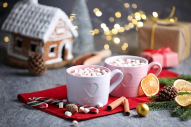 Gri masada lokum, tarçın ve Noel dekoru olan lezzetli kakao bulanık ışıklara karşı, yakın plan.