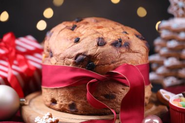 Noel yemeği. Lezzetli Panettone keki, zencefilli kurabiye, şekerli meyve ve dekorasyon masasında bulanık ışıklara karşı, yakın plan. Bokeh etkisi