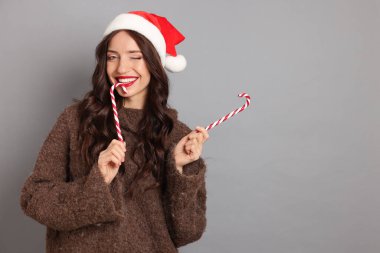 Noel Baba ve şeker kamışlı güzel bir kadın. Gri arka planı var. Mesaj için yer var. Noel sezonu