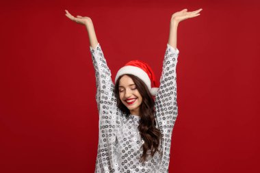 Kırmızı arka planda Noel Baba şapkalı güzel bir kadın. Noel sezonu