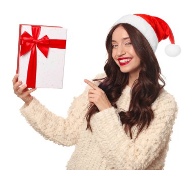 Noel Baba şapkalı güzel kadın beyaz arka planda Noel hediyesini gösteriyor.
