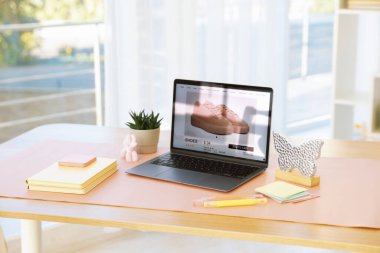 Ofisteki ahşap masada dizüstü bilgisayarı, dekoru ve pembe paspası olan şık bir iş yeri.
