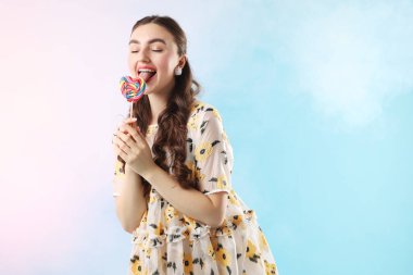 Açık mavi arkaplanda lolipopu olan, dumanlı, metin için alanı olan bir kadın