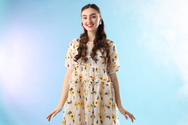 Açık mavi arka planda, dumanlı, güzel giyimli genç bir kadın.